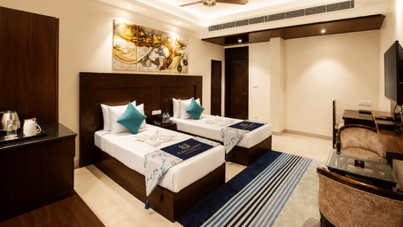 Deluxe Twin room with two single beds, artwork and a dressing table at Eastlynn Resort, Rishikesh.