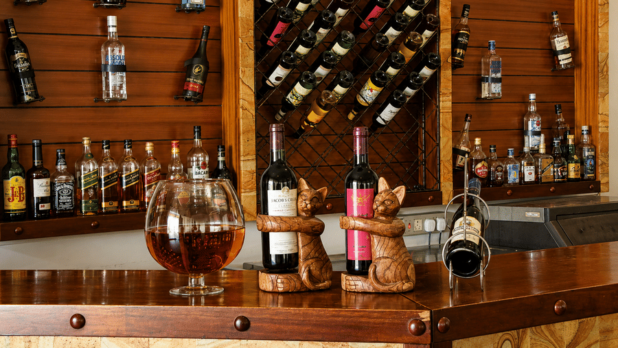 Paanam - The Bar shelf stocked with a curated selection of wines and spirits, set against warm wooden shelving and lighting
