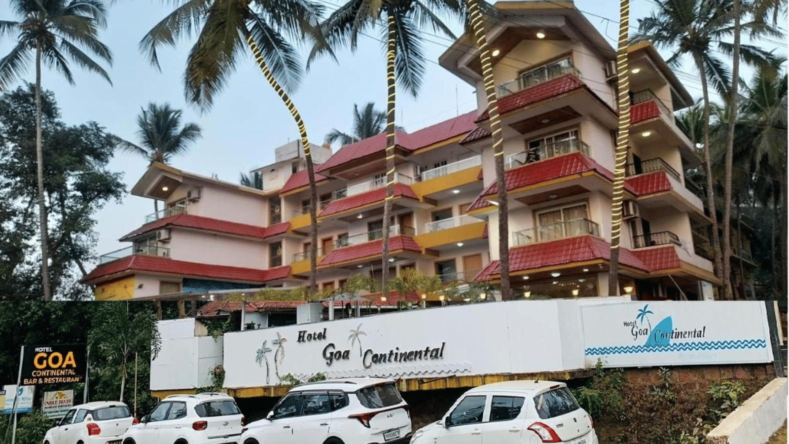 An exterior view of Perfectstayz Premium Goa Continental building with palm trees and several cars parked in the front lot.