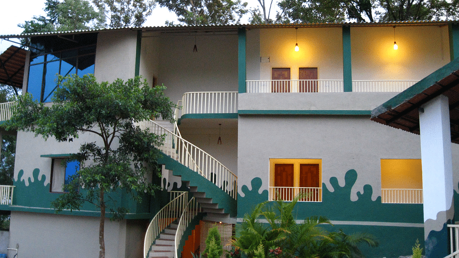 Facade of an accommodation with lights in the balcony and surrounded by plants  at Coorg Jungle Camp Backwater Resort, Kushalnagar.