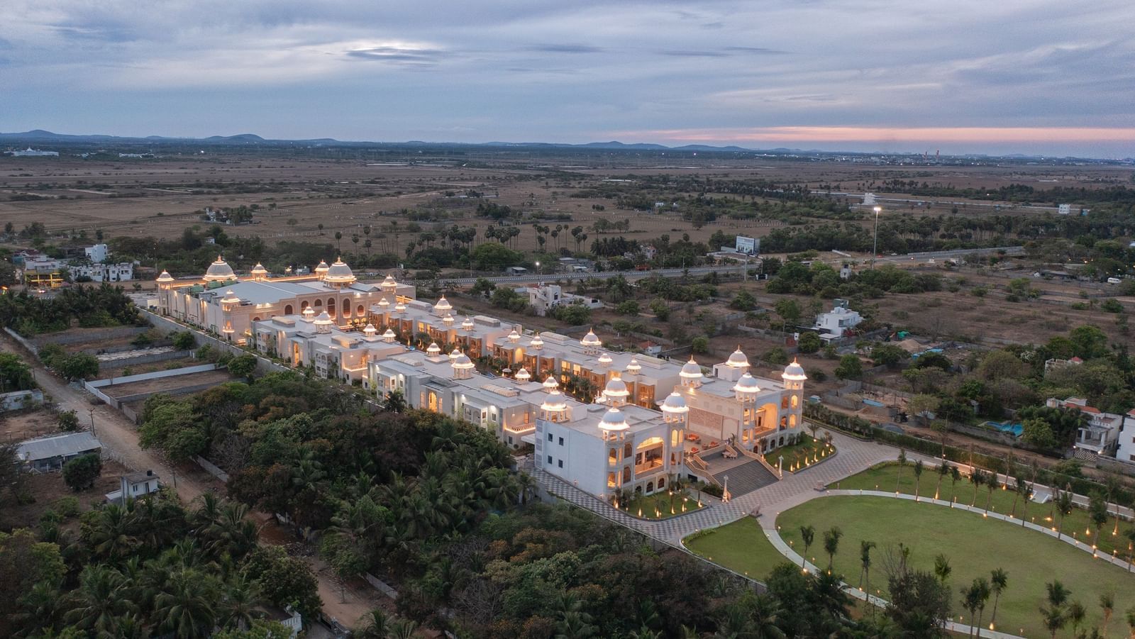 An aerial shot of the beautifully lit Kaldan Samudhra Palace in Mahabalipuram surrounded by lush greenery on all sides