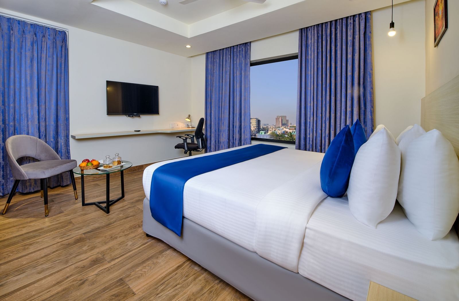 A room at Essentia Premier Hotel, Chennai with a double bed, a television and a work desk and chair