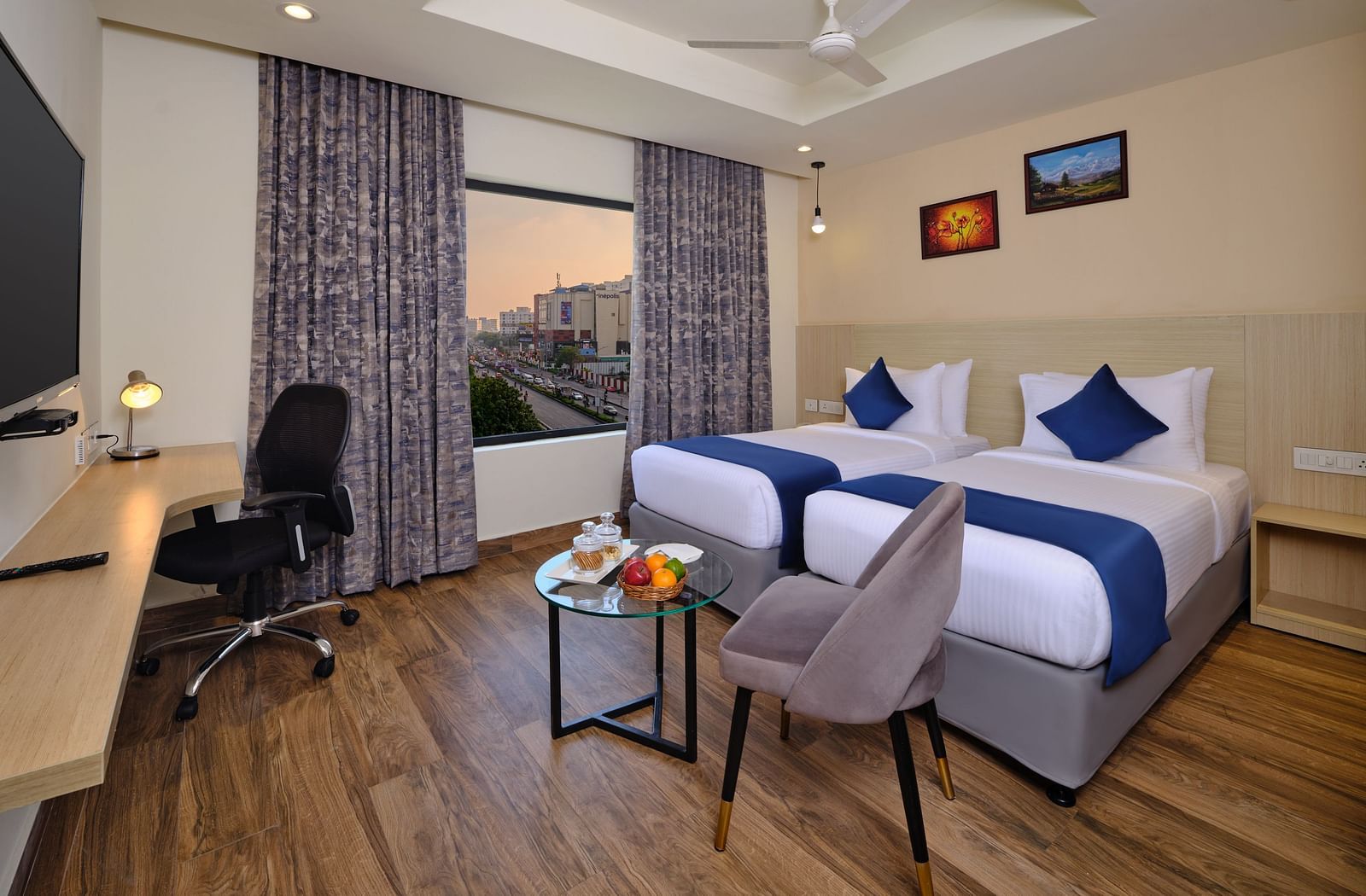 A room at Essentia Premier Hotel, Chennai with twin beds, a television and work desk and chair