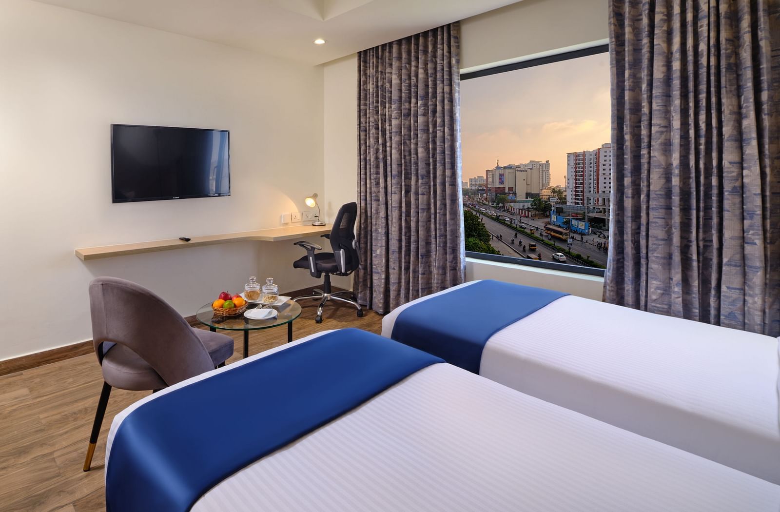A room at Essentia Premier Hotel, Chennai with twin beds, a television and a work desk and chair