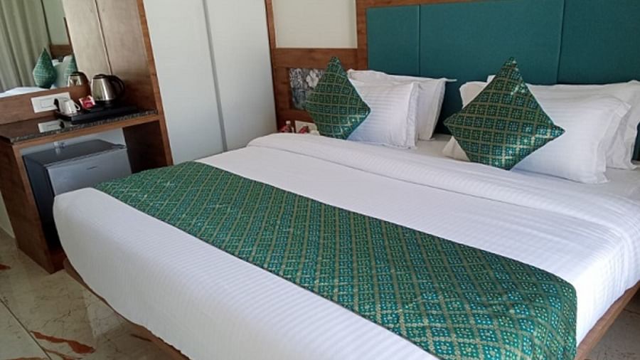 A room with a large bed which is neatly made with bedsheet, pillows and bedside tables at Angel Lords Eco Inn Amreli.