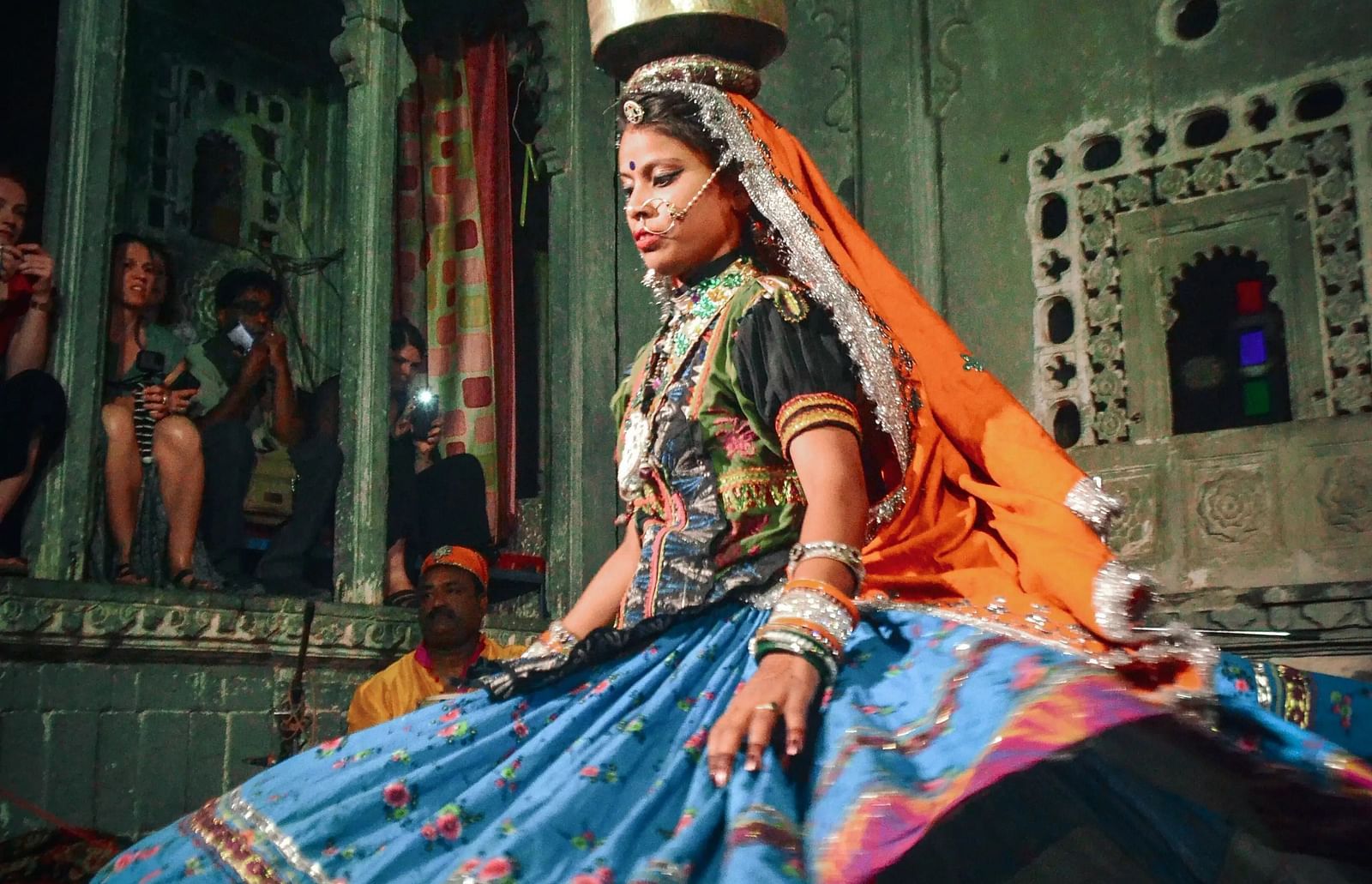  A woman in traditional attire is dancing. She is wearing a patterned skirt and a head covering.