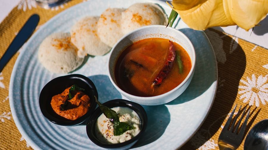 A close-up view of a plate with idlis and three bowls of side dishes at BluSalzz Villas - The Green Roof, Bhimtal.