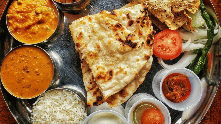 A neatly arranged plate with several Indian delicacies served.