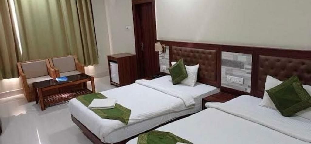 A twin room with white linen and green cushions, ideal for a comfortable and relaxed visit - Pemaling Lords Eco Inn Guwahati