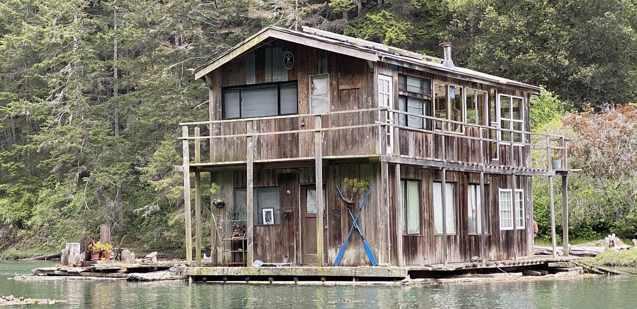 A broken house in the water with trees in the background
