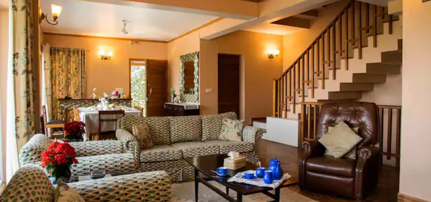 A living area with comfortable sofas in front of the staircase at SOUTHGATE KASAULI BY ZENQ.