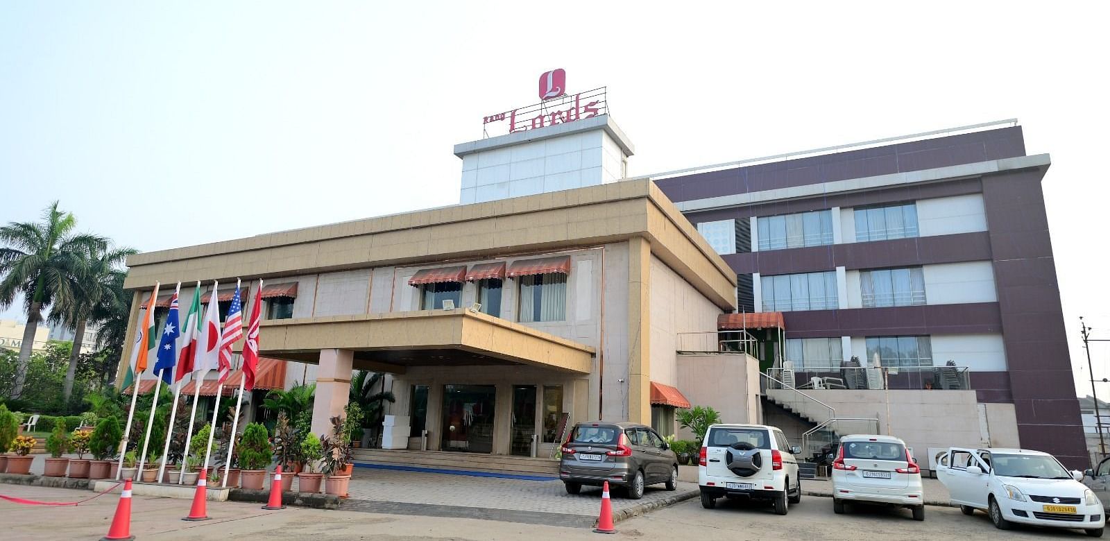 Facade of Rang Lords Inn, Bharuch, with its distinctive architecture, entrance, and parked vehicles on a bright day