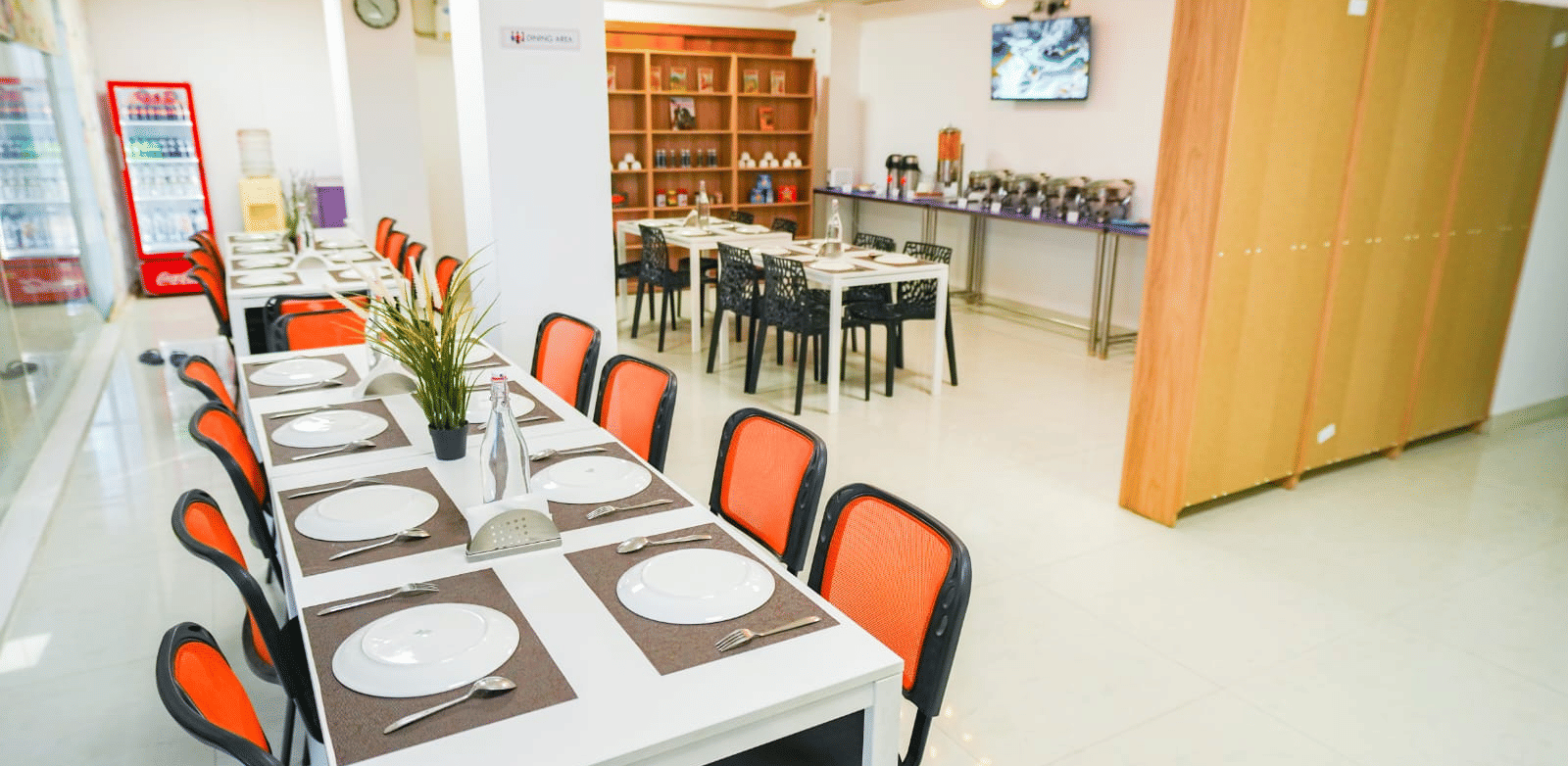 An indoor dining area featuring a long table with placemats and chairs neatly arranged around it, and a serving counter to the side at Sunrise A Boutique Hotel, Hyderabad.