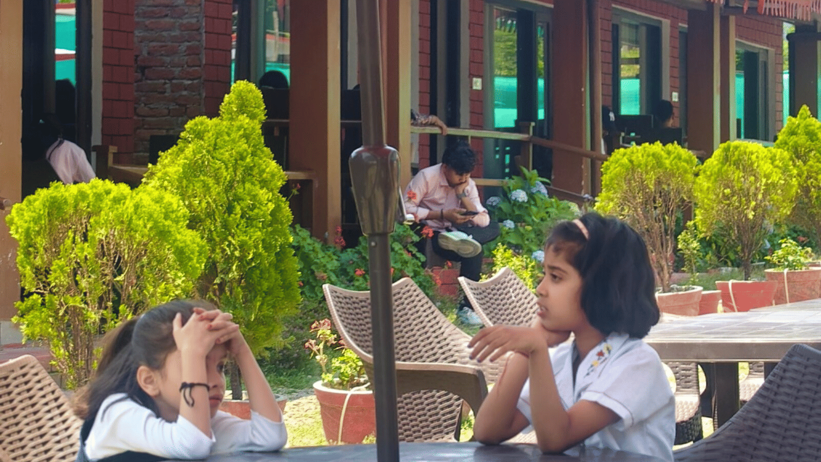Children sitting at an outdoor table under an umbrella in the garden of Sol Glow Resort, Bhowali.