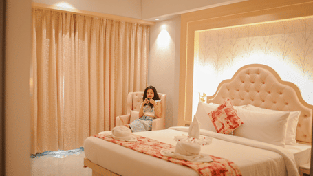 Guest seated on a bed in a softly lit room at Hotel Mumbai House Digha, Airoli.