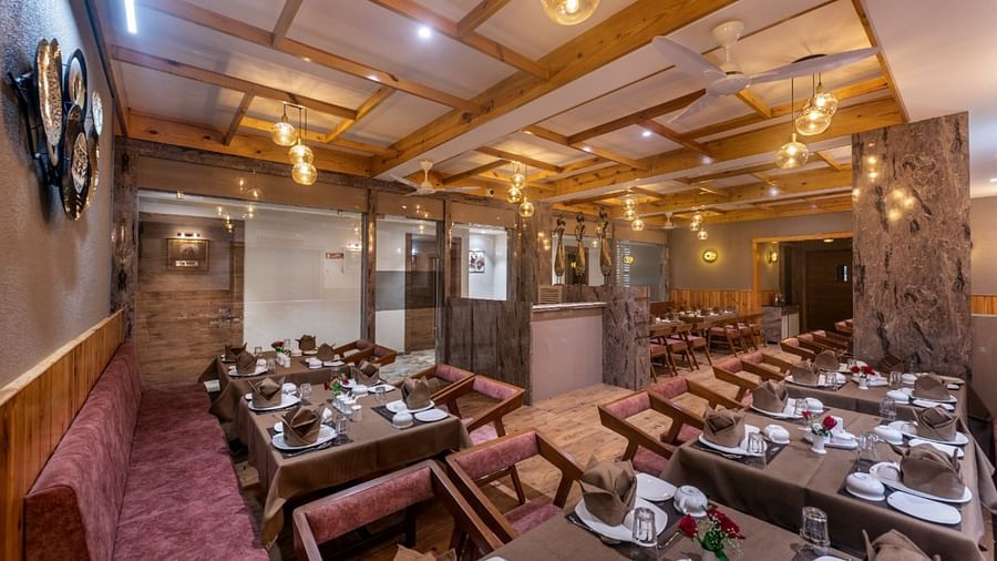 A dining area with multiple tables and chairs set under warm lighting at Angel Lords Eco Inn Amreli.