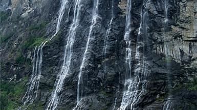view of water falls cascading down the rocky hills into a waterbody