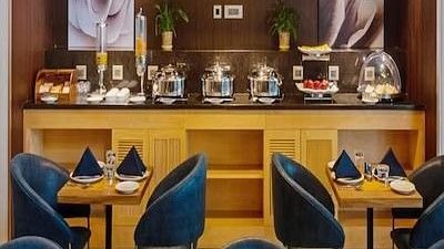 A restaurant seating area with a chairs and tables set for diners and a buffet area at Hotel Saket 27, New Delhi