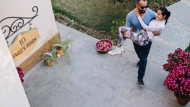 Two people standing and on a paved outdoor walkway near pink flowers and a villa at Karma Chalets.