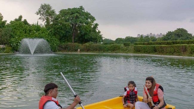 Group of people paddling a bright yellow boat in a lake with a water fountain in the background at Karma Chalets.