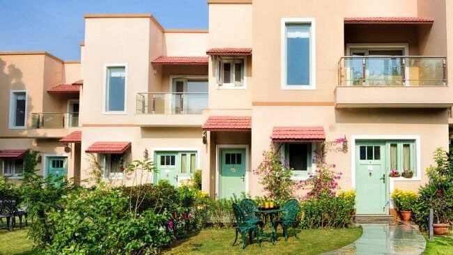 Row of peach-coloured two-storey villas with balconies and manicured front gardens at Karma Chalets.