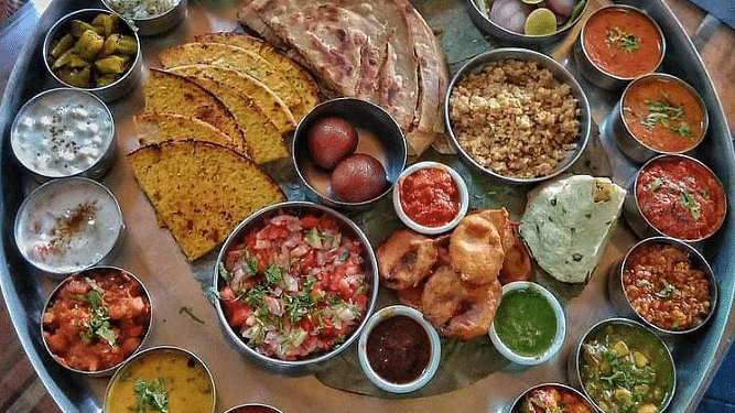 A top view of a Rajasthani thali, showcasing a variety of traditional dishes beautifully arranged on a large plate, celebrating the rich flavours of Rajasthan.