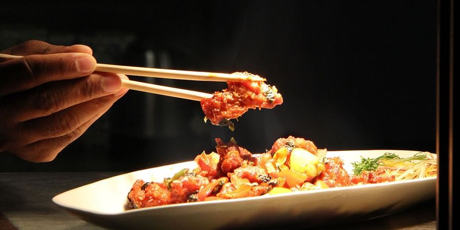 A person delicately picking up food with chopsticks.