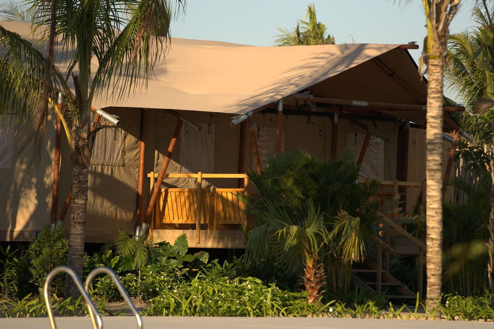 A tropical-style Mindful Tent at WoCAL Retreat Ke Ga with a thatched roof and private pool surrounded by palm trees.