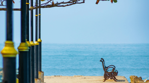A solitary steel outdoor seat next to the Arabian Sea in Fort Kochi as seen from afar.
