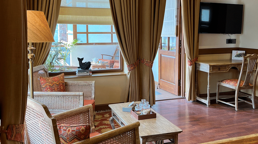 Superior Lake Facing seating area at Fishermen's Lodge, Bhimtal, featuring a chair, lamp, TV, and work desk for a comfortable stay.