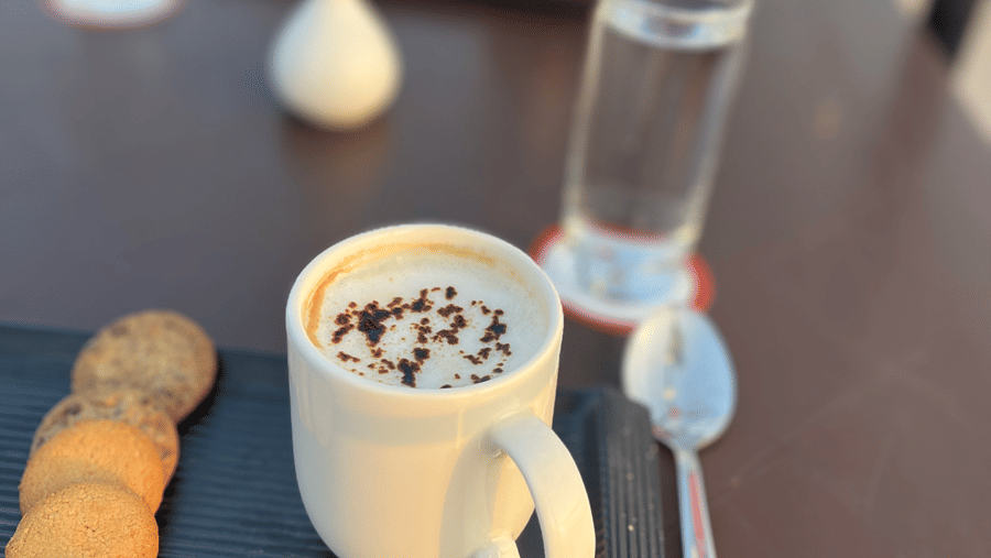 A frothy coffee and snacks neatly arranged on the table - Senses Hotel