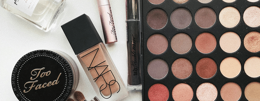 Beauty cosmetic products arranged on a table, featuring brushes and a vibrant color palette