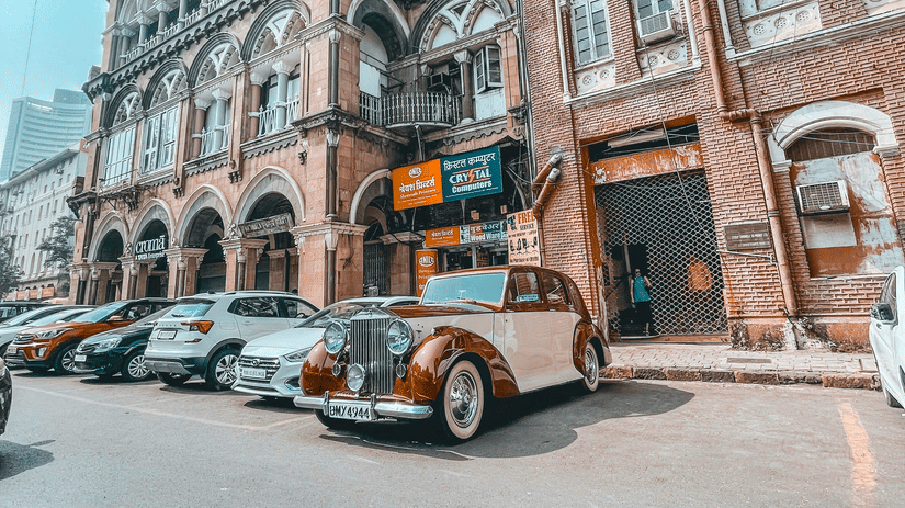 A view of Colaba Causeway with a vintage car parked in front of a building.