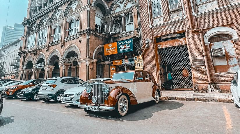 A view of colaba causeway with a vintage car parked in front of a building