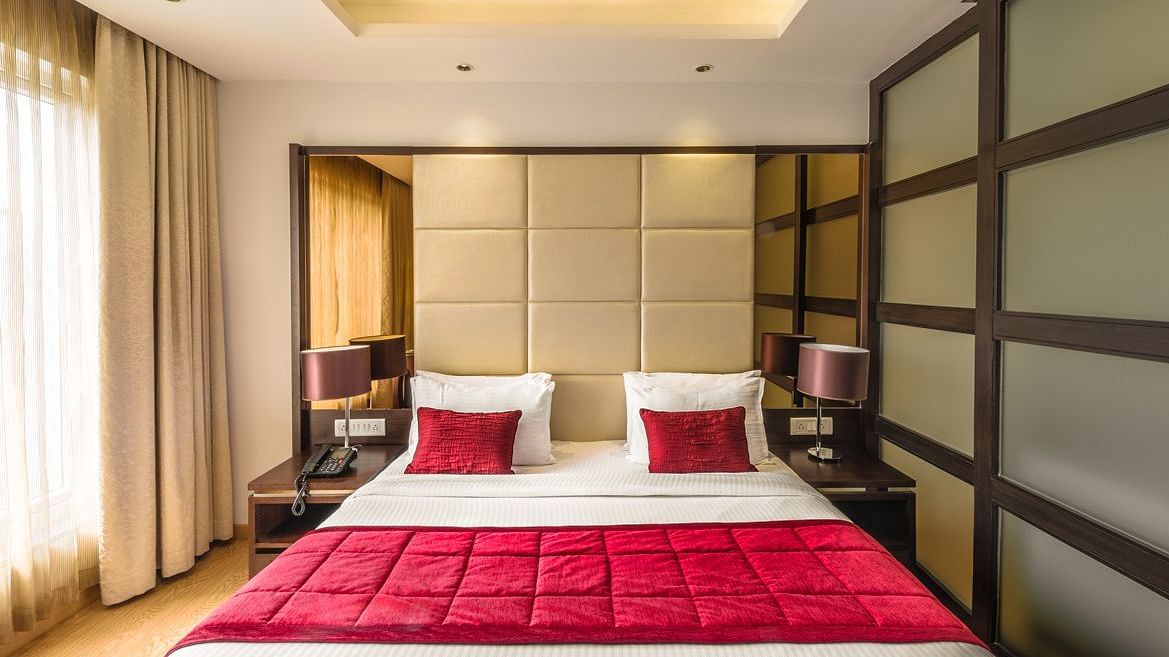 A Hotel bedroom with large bed, red bedspread and padded headboard - TGI Grand Fortuna, Hosur