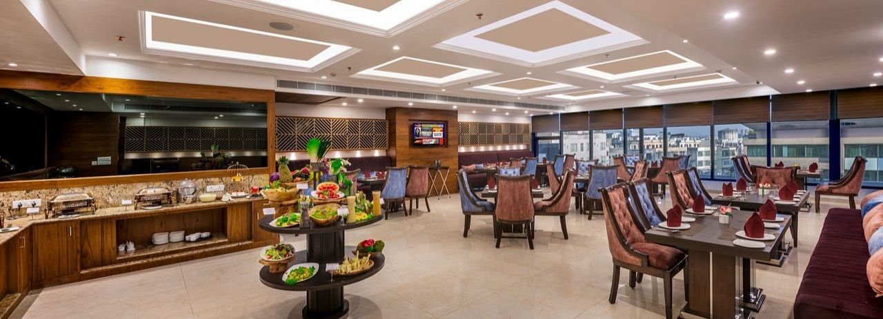 Elegant restaurant interior with multiple dining tables, cushioned chairs, and modern ceiling lighting.