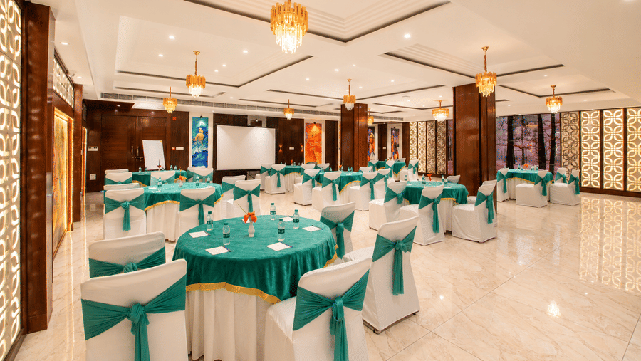 Banquet hall set up with round tables in teal and gold linen for an event at Eastlynn Resort, Rishikesh.
