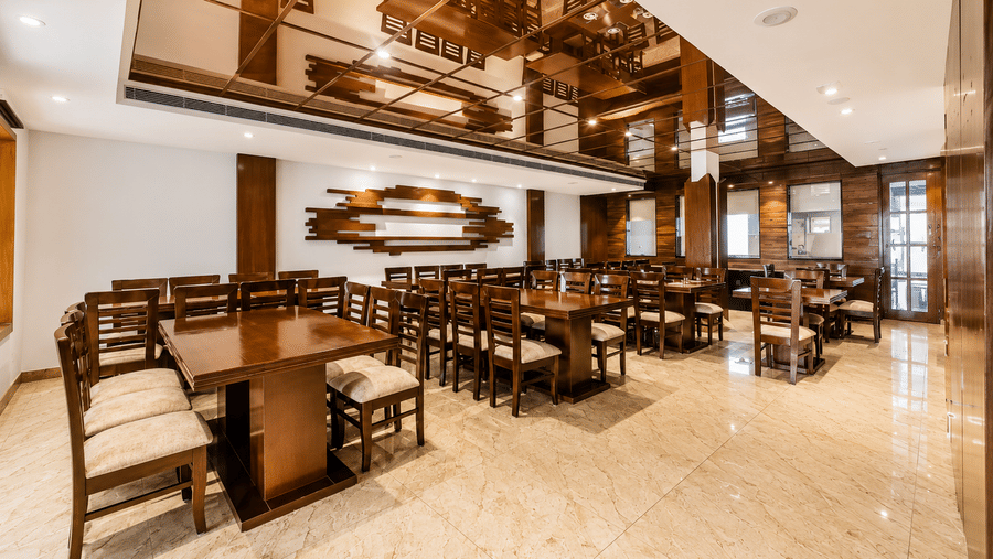 Wide view of restaurant dining area with wooden furniture and warm lighting at Eastlynn Resort, Rishikesh.