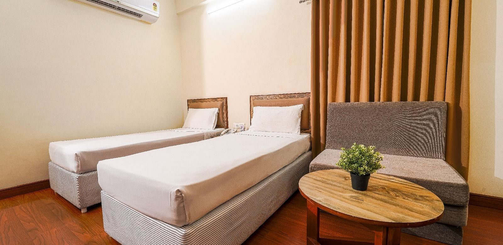Hotel room with two single beds, a comfortable couch, and a coffee table in Hyderabad near Ramoji Film City.