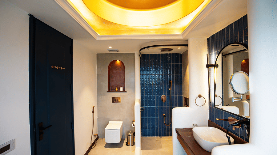 A bathroom layout with a wall-mounted toilet, a blue tiled shower enclosure, and a vanity counter at The Sierra - By The Lake.