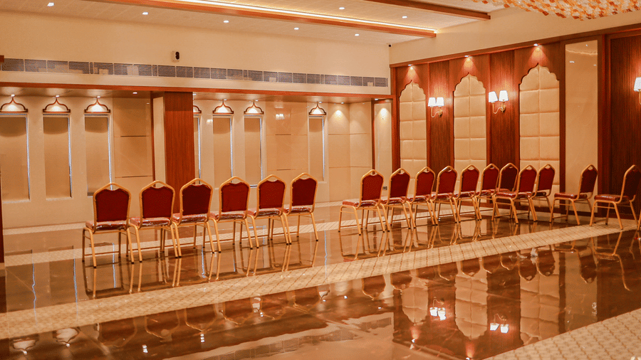 Rows of red and gold chairs set up in a spacious hall with a glossy floor at Hotel Mumbai House Digha, Airoli.