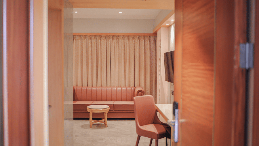 Seating area with curtains and wooden door frame at Hotel Mumbai House Digha, Airoli.