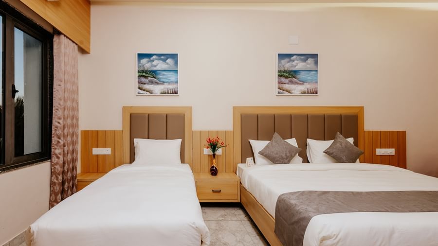 Front view of a well-arranged bedroom at Daksh The Grand Gowardhan, Dwarka, featuring multiple beds and headboards.