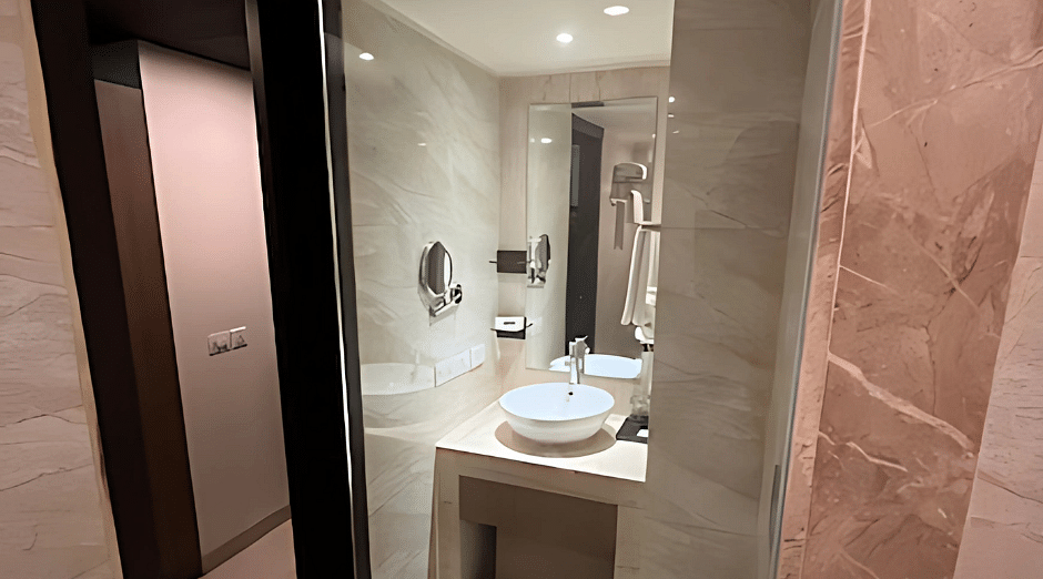 A portrait image of a washroom with fancy white commodes and glass covered bathing area.