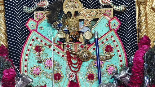 A colourful, detailed shrine with statues of Hindu gods inside. The idols are adorned with beautiful, elaborate clothing.