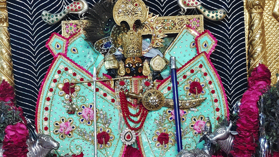 A colourful, detailed shrine with statues of Hindu gods inside. The idols are adorned with beautiful, elaborate clothing.