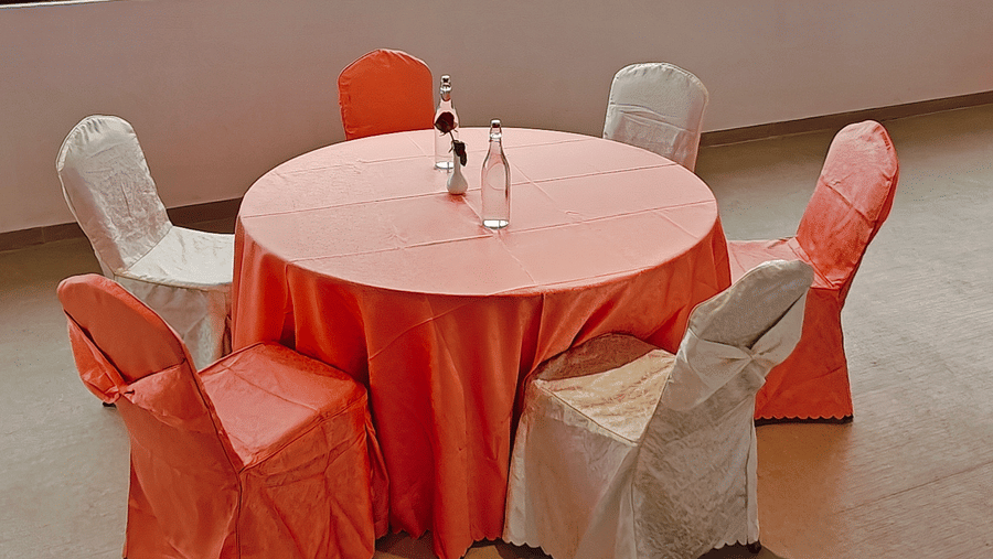 A single round table with 5 chairs is positioned by a large window overlooking hills at Bliss Casa Mila By Bergamont Hotels, Kodaikanal.