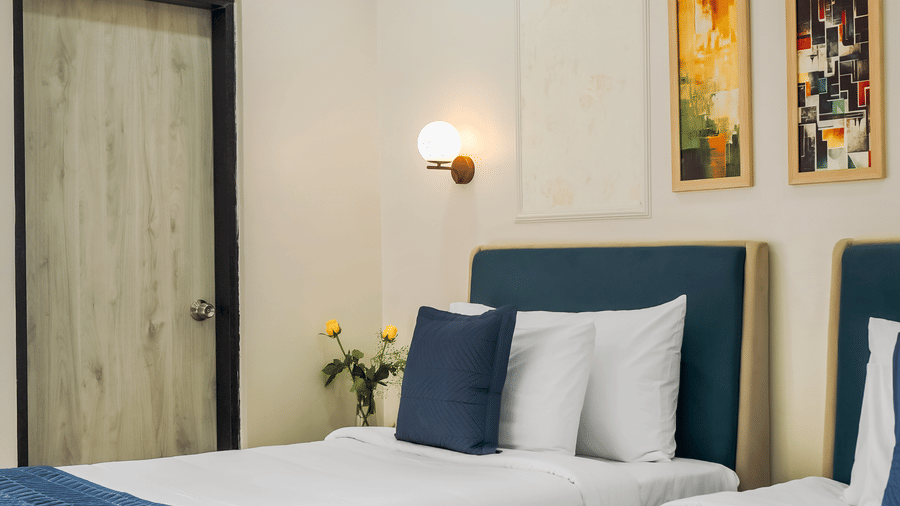 A hotel room at Urban Suites by BluSalzz, Jaipur, featuring a bed with white and linens, a door, and wall art.