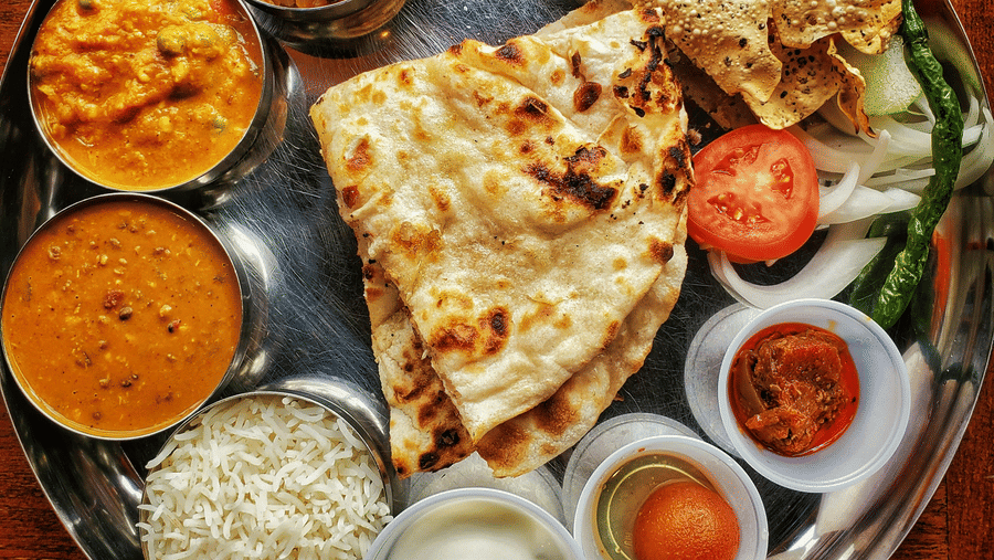A neatly arranged plate with several Indian delicacies served.