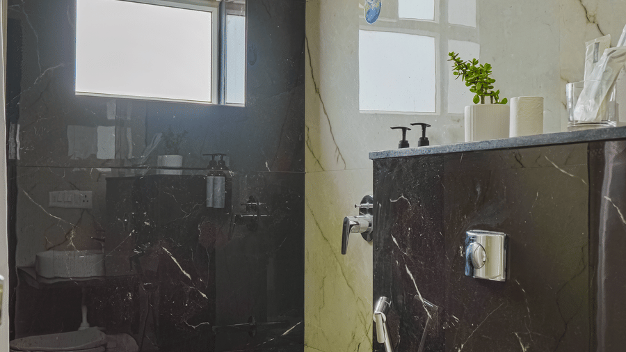 A hotel room bathroom at Urban Suites by BluSalzz, Jaipur, with a toilet, a door, and tiled walls.